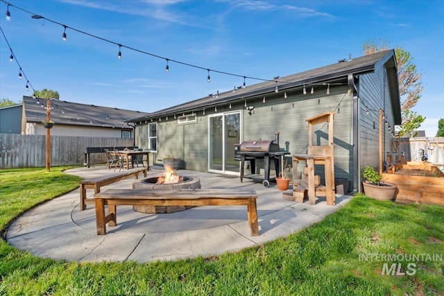back of property featuring a lawn, a patio, fence, and a fire pit