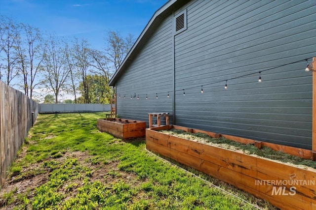 view of side of home with a lawn, a garden, and a fenced backyard
