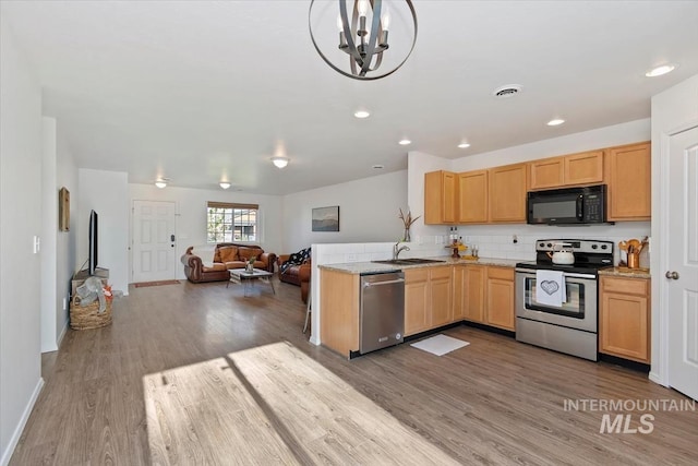 kitchen with a sink, stainless steel appliances, open floor plan, wood finished floors, and visible vents