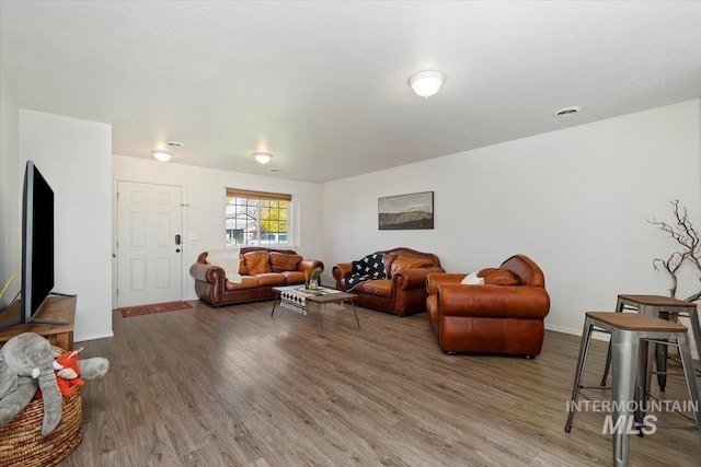 living area with baseboards and wood finished floors