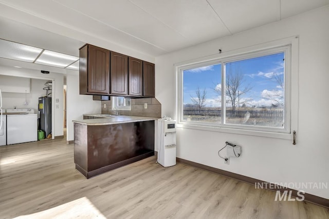 kitchen with electric water heater, sink, washer and dryer, dark brown cabinets, and light hardwood / wood-style floors