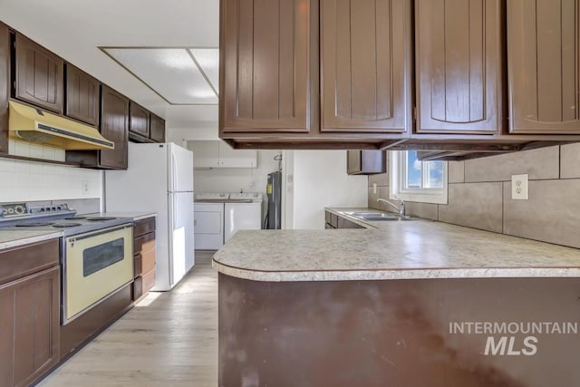 kitchen with white appliances, dark brown cabinetry, sink, separate washer and dryer, and light hardwood / wood-style flooring