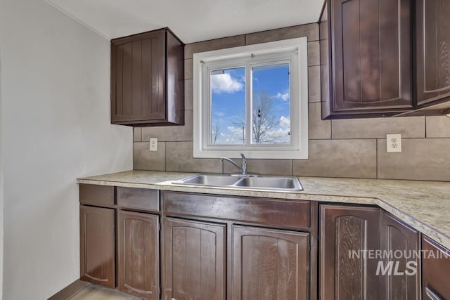 kitchen featuring dark brown cabinetry, tasteful backsplash, and sink