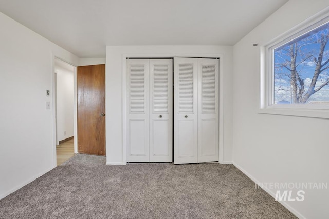 unfurnished bedroom featuring light colored carpet and a closet