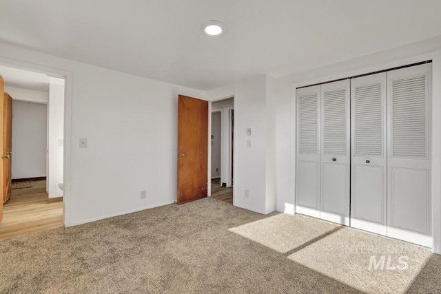 unfurnished bedroom featuring a closet and light colored carpet