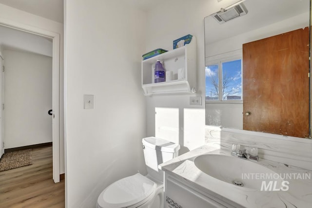 bathroom with hardwood / wood-style floors, vanity, and toilet