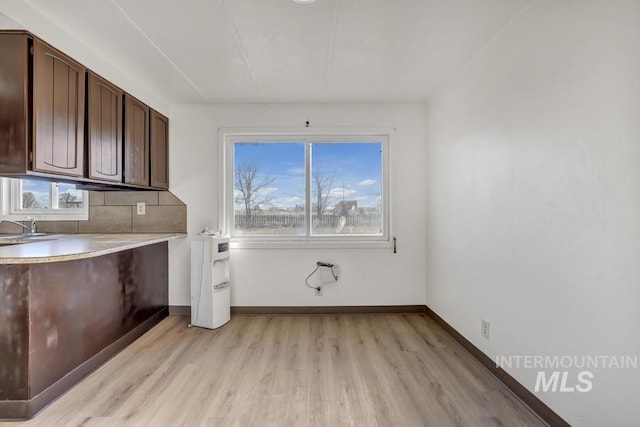 laundry area with light hardwood / wood-style flooring, a wealth of natural light, and sink