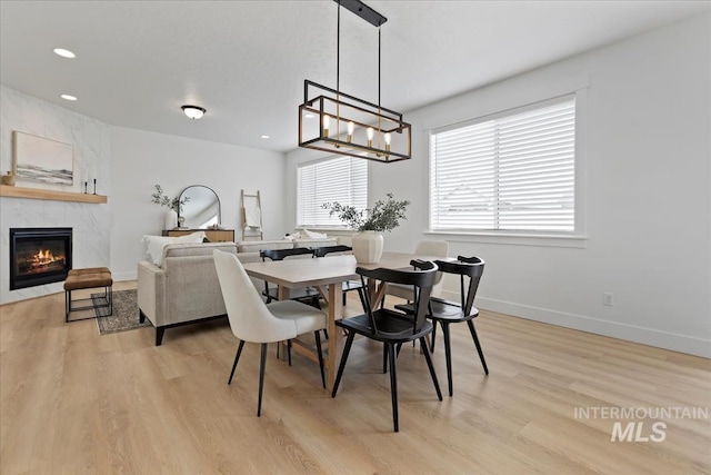 dining room featuring a notable chandelier, recessed lighting, a high end fireplace, light wood-type flooring, and baseboards