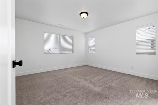 carpeted spare room featuring visible vents and baseboards