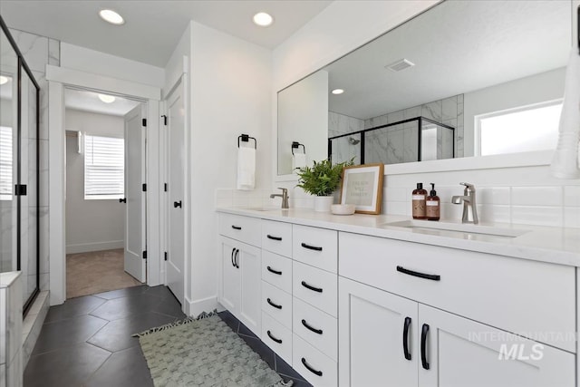 bathroom featuring double vanity, a stall shower, a sink, and visible vents