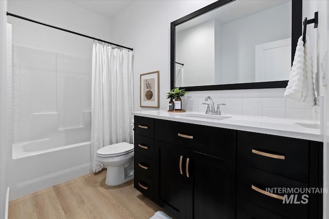 full bath with toilet, wood finished floors, vanity, backsplash, and shower / bath combo