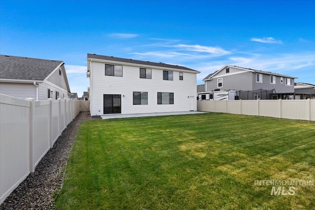 rear view of property featuring a fenced backyard and a yard