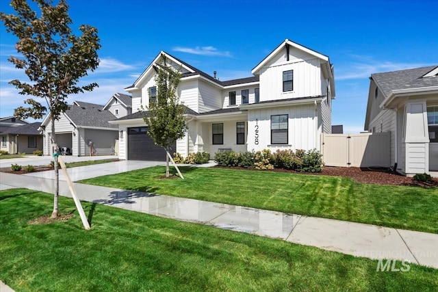 modern farmhouse with concrete driveway, board and batten siding, a front yard, fence, and a garage