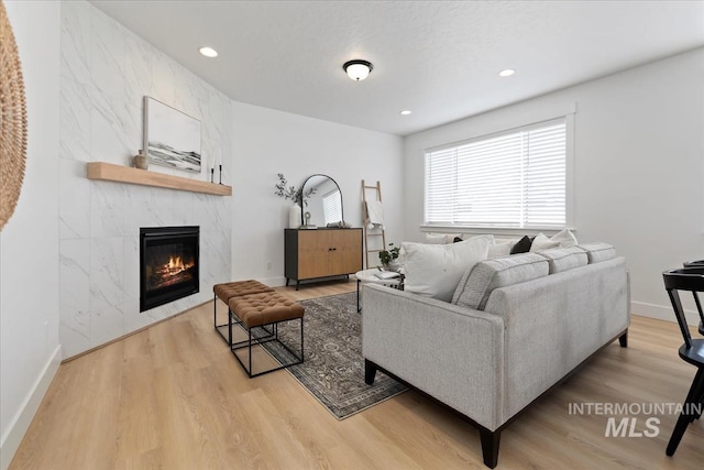 living room with recessed lighting, baseboards, a premium fireplace, and wood finished floors