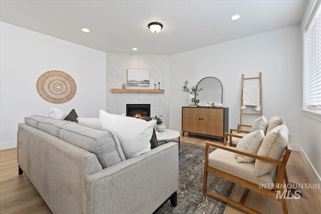 living area with a large fireplace, recessed lighting, wood finished floors, and baseboards