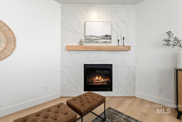 interior space featuring a tile fireplace, baseboards, and wood finished floors