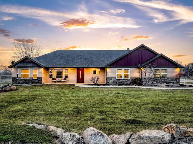 view of front of home featuring a yard, stone siding, and board and batten siding