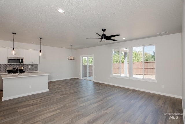 unfurnished living room featuring ceiling fan, dark hardwood / wood-style floors, and a healthy amount of sunlight