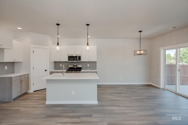 kitchen with white cabinets, decorative backsplash, stainless steel appliances, and hanging light fixtures