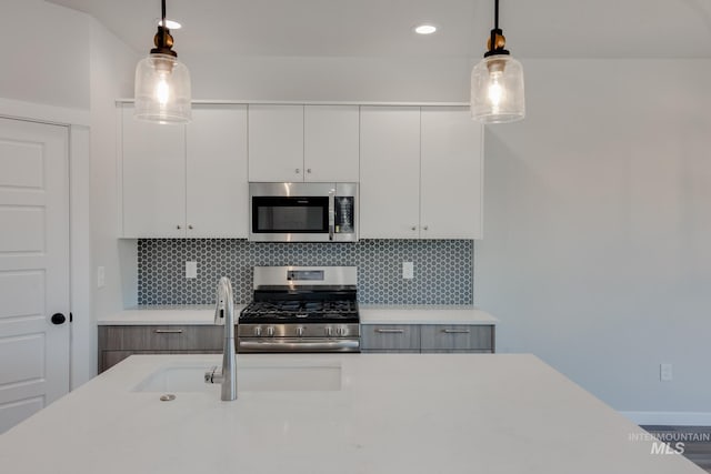 kitchen featuring decorative light fixtures, decorative backsplash, white cabinetry, and stainless steel appliances