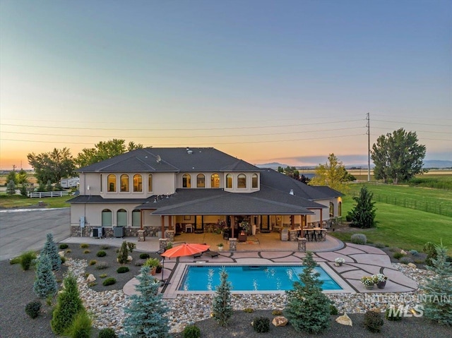 9105 W Mcmillan, Nampa, ID 83687 - back of property at dusk with a patio area, an outdoor pool, stucco siding, and cooling unit