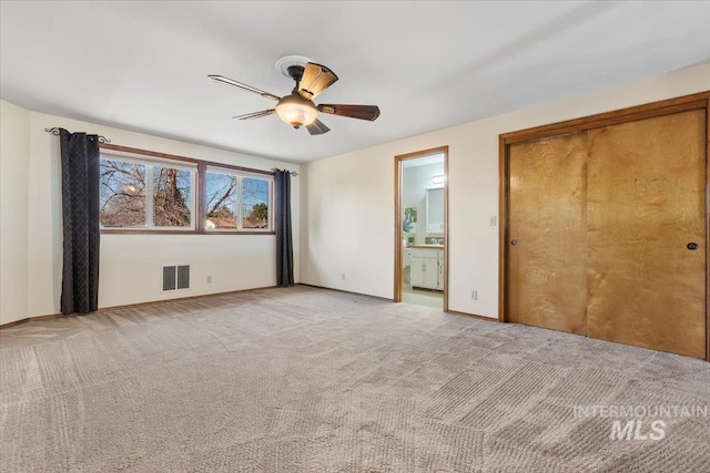 unfurnished bedroom with ceiling fan, light colored carpet, and ensuite bathroom