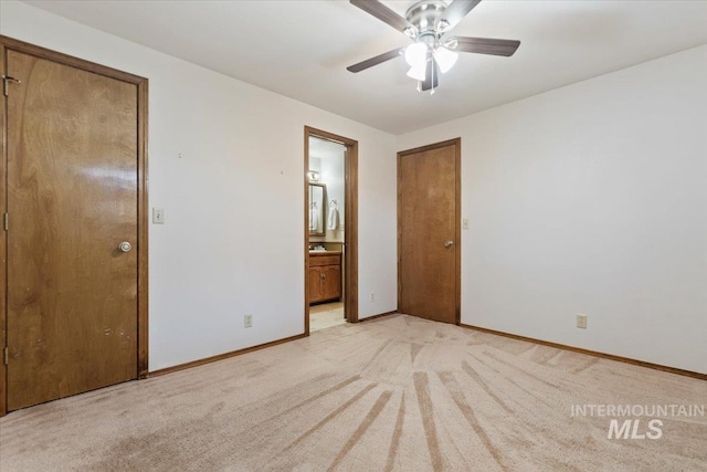 unfurnished bedroom with ensuite bathroom, light colored carpet, and ceiling fan