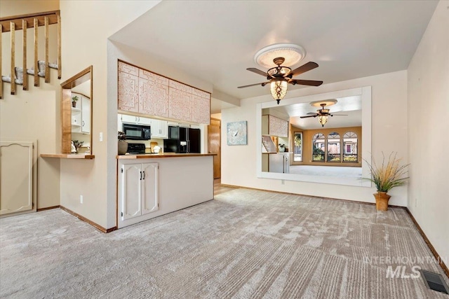 kitchen featuring ceiling fan, black appliances, and light carpet