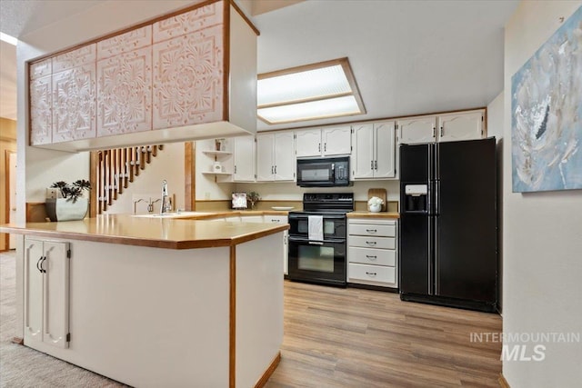 kitchen with black appliances, white cabinetry, sink, kitchen peninsula, and light hardwood / wood-style flooring