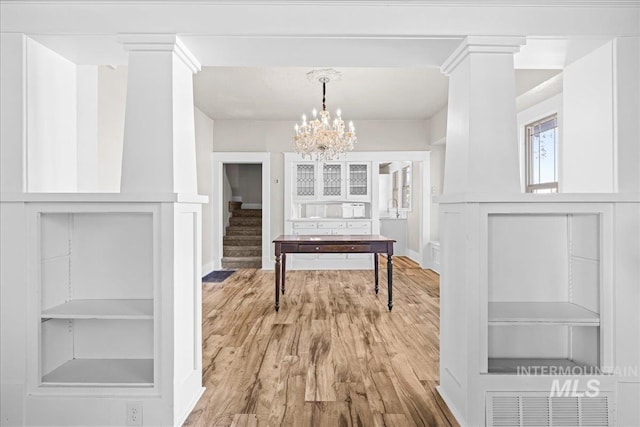 803 4th St S, Nampa, ID 83651 - hallway featuring built in shelves, decorative columns, an inviting chandelier, and wood finished floors