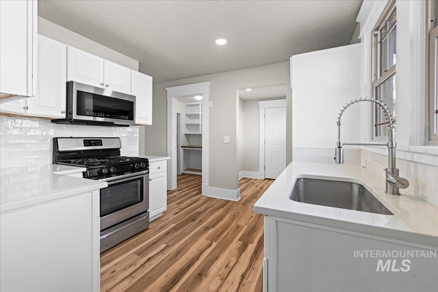 803 4th St S, Nampa, ID 83651 - kitchen with light wood-style floors, a sink, stainless steel appliances, decorative backsplash, and baseboards