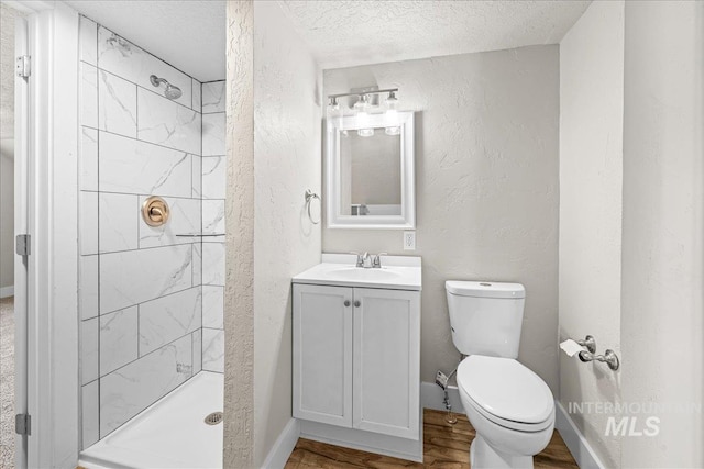 803 4th St S, Nampa, ID 83651 - bathroom featuring a tile shower, a textured ceiling, vanity, toilet, and wood finished floors