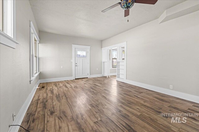 803 4th St S, Nampa, ID 83651 - unfurnished living room with baseboards, a textured ceiling, a ceiling fan, and wood finished floors
