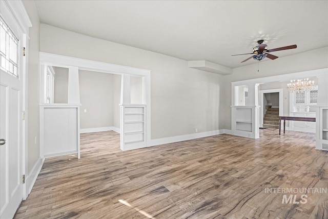 803 4th St S, Nampa, ID 83651 - unfurnished living room featuring ceiling fan with notable chandelier, wood finished floors, baseboards, and stairway