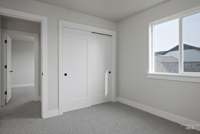 unfurnished bedroom with light colored carpet and a closet