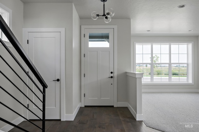 entryway with dark wood-type flooring and a notable chandelier