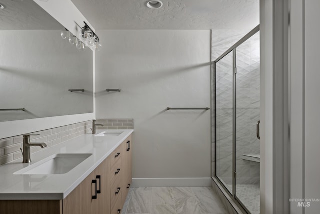 bathroom with vanity, a textured ceiling, backsplash, and a shower with shower door