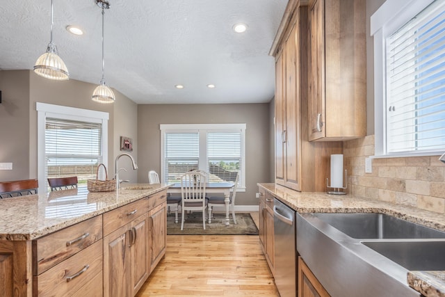 120 S Marko Ln, Kuna, ID 83634 - kitchen with stainless steel dishwasher, light wood finished floors, brown cabinets, a sink, and decorative backsplash
