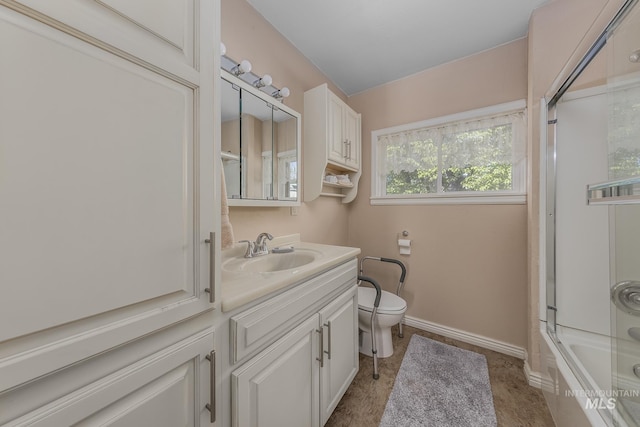 full bath featuring toilet, baseboards, vanity, and bath / shower combo with glass door