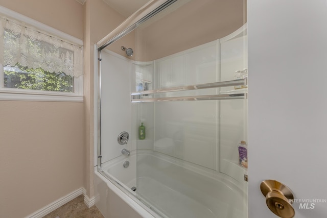full bathroom featuring combined bath / shower with glass door and baseboards