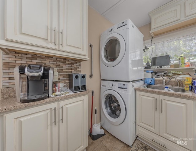 washroom with cabinet space, light tile patterned floors, a sink, and stacked washer and dryer