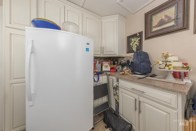 kitchen featuring freestanding refrigerator, light countertops, white cabinetry, and decorative backsplash