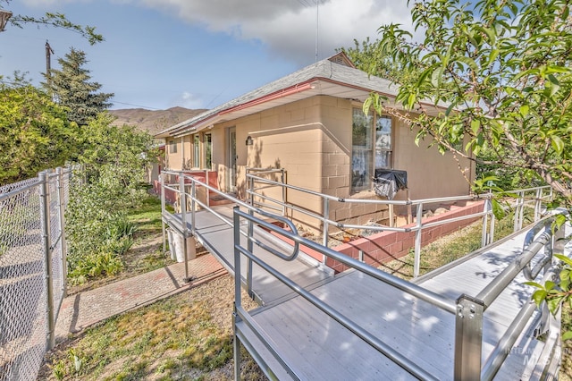 view of side of home with concrete block siding, fence, and a mountain view