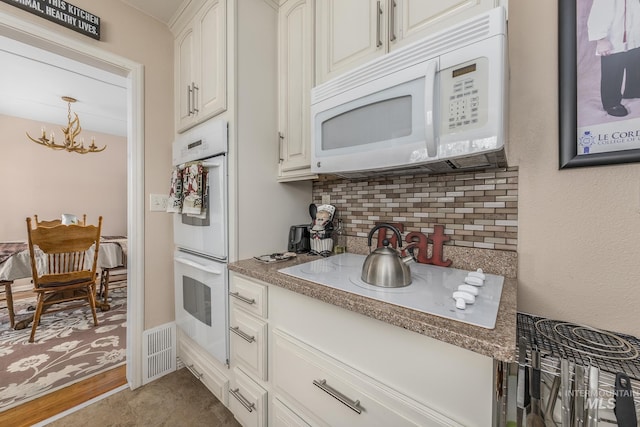 kitchen featuring a chandelier, stone countertops, white cabinetry, white appliances, and decorative backsplash