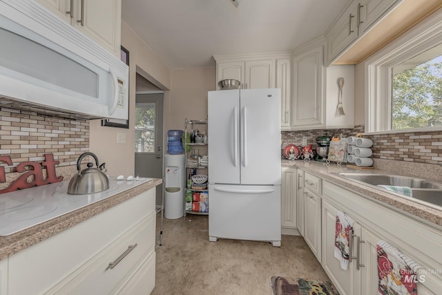 kitchen featuring white appliances, a sink, decorative backsplash, light countertops, and white cabinets