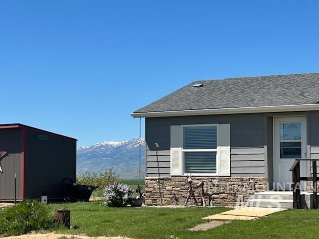 16 E 300 S Unit 16E 300S, Fairfield, ID 83327 - view of property exterior featuring a mountain view, stone siding, a lawn, and a shingled roof