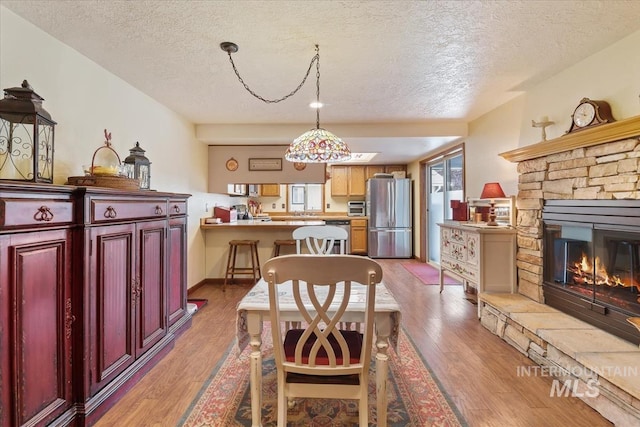 1460 Fairway Ct, Mountain Home, ID 83647 - dining room with a textured ceiling, light wood finished floors, and a fireplace