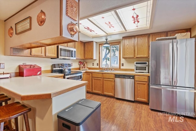 1460 Fairway Ct, Mountain Home, ID 83647 - kitchen with appliances with stainless steel finishes, a peninsula, a breakfast bar area, light wood-style floors, and light countertops