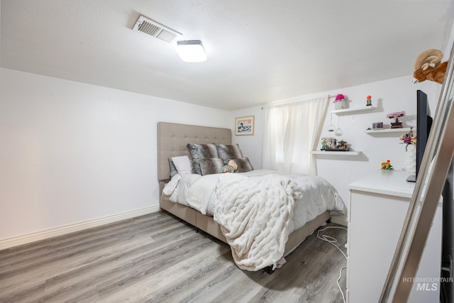 bedroom featuring light hardwood / wood-style floors and a textured ceiling