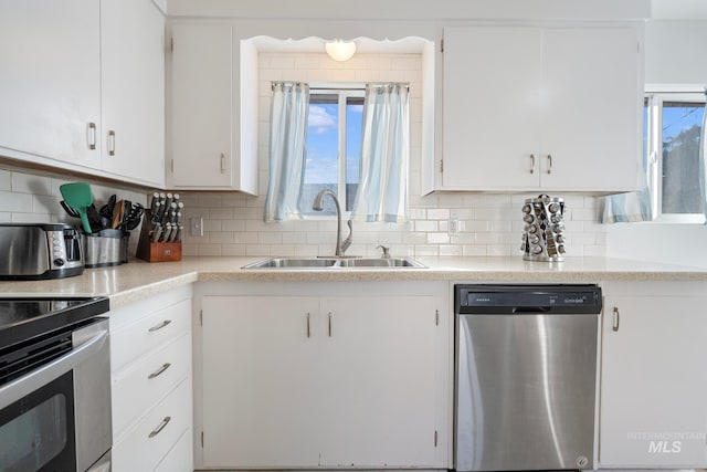 kitchen with tasteful backsplash, appliances with stainless steel finishes, sink, and white cabinets